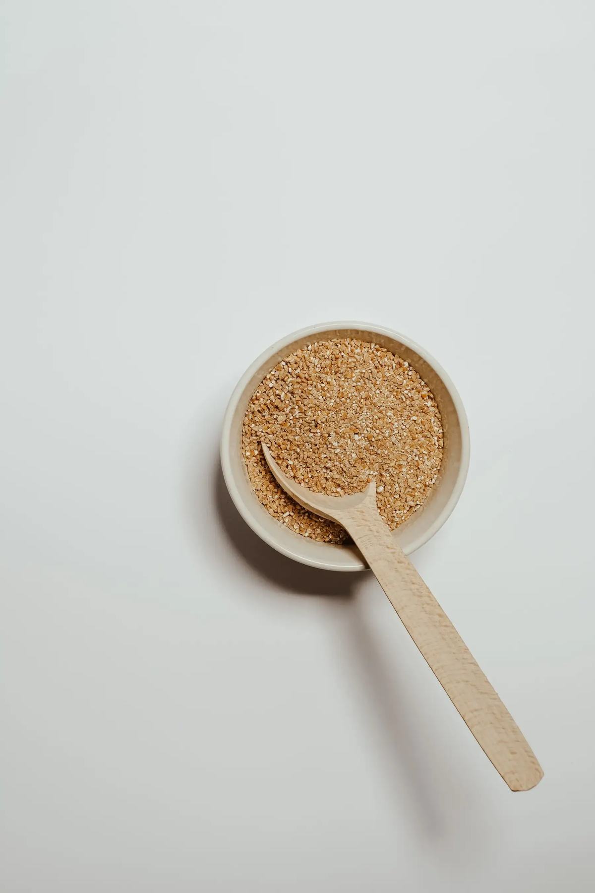 Psyllium husk in a bowl beside whole psyllium seed